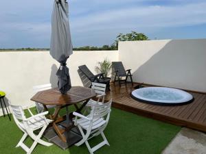 a patio with an umbrella and a table and chairs at Appartement avec SPA Camargue 4 couchages in Saint-Laurent-dʼAigouze