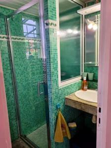 un bagno piastrellato verde con lavandino e doccia di CHALET 311 KHELUS CLUB a Gujan-Mestras