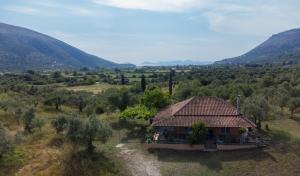 a small house in a field with mountains in the background at Helen's house in Igoumenitsa