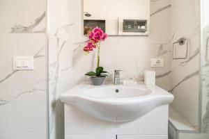 a white bathroom with a sink with a flower on it at Casetta Lago Maggiore in Maccagno Superiore