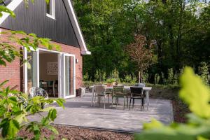 un patio avec une table et des chaises à côté d'un bâtiment dans l'établissement Luxe Vakantiehuis Ruwe Iep Veluwe, à Nunspeet