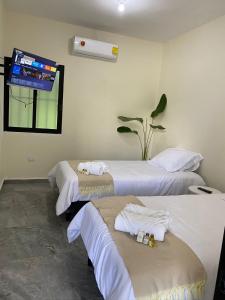 a room with three beds and a tv on the wall at Hotel La Isla in Cunduacán