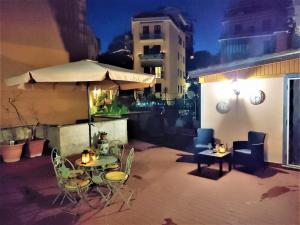eine Terrasse mit einem Tisch, Stühlen und einem Sonnenschirm in der Unterkunft Vatican Heart Leone Apartment at Roman Terrace in Rom
