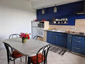 Aux murmures de la nature في Vaunaveys: مطبخ مع دواليب زرقاء وطاولة عليها ورد