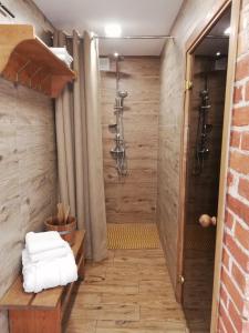 a shower in a bathroom with a wooden wall at "Šventvakarė" in Liaunai