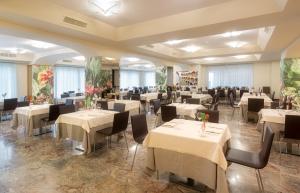 una sala da pranzo con tavoli e sedie bianchi di Sangallo Palace a Perugia