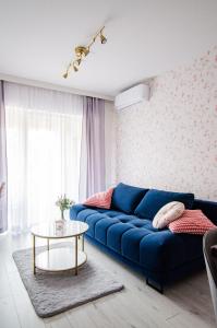 Sofá azul en la sala de estar con mesa en Apartament KARMEL, en Przemyśl