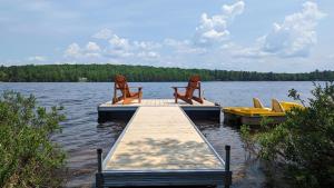 a dock with chairs sitting on top of a lake at Lake House Chalet Laurentians in Nominingue