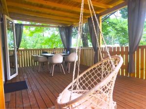 a hammock on a deck with a table and chairs at Mobilna hiška pogled na jezero in Velenje