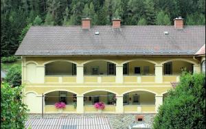 a large yellow house with a roof with pink flowers at Charmante Ferienwohnung in St. Barbara im Mürztal in Grossveitscherthal