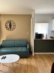sala de estar con sofá verde y reloj en la pared en Bel appartement à 25 mn de Paris, en Sartrouville
