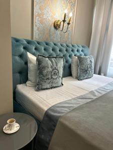 a bed with a blue headboard and pillows on it at Family Residence Boutique Hotel in Lviv