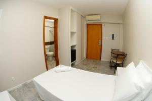 a bedroom with a white bed and a bathroom at Rede Andrade Pampulha in Belo Horizonte