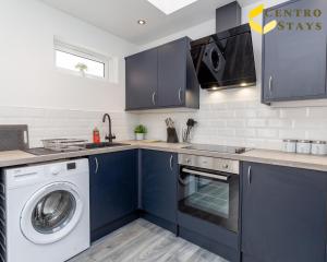 a kitchen with blue cabinets and a washer and dryer at 5-10percent Off Week or Month Stay - Group, Family or Work Relocation FREE PARKING in Northampton