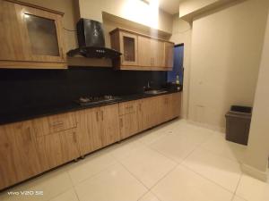 イスラマバードにあるAQZ Apartmentsのキッチン(木製キャビネット、黒いカウンタートップ付)