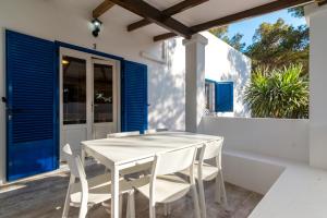 un tavolo bianco con sedie su un balcone con persiane blu di Apartamentos Verdera Es Pujols a Es Pujols