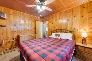 a bedroom with a bed and a ceiling fan at Cozy Carp Lake Cottage with Dock, 4 Kayaks and Fire Pit in Carp Lake