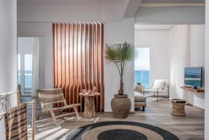 un soggiorno con un vaso con una palma di Khroma Luxury Suite 1 Beach front apartment a Hersonissos