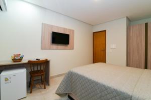 a bedroom with a bed and a desk and a television at Star Hotel Limoeiro in Limoeiro