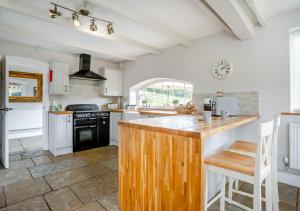 cocina con armarios blancos y encimera de madera en Hafod Ganol Farm en Trehafod