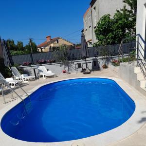 a large blue swimming pool in a yard with chairs at IGGY in Malinska