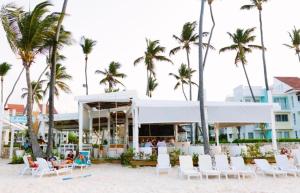 a resort on the beach with chairs and palm trees at 1BDR Private Beach Access at Los Corales PuntaCana in Punta Cana
