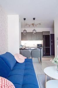 a living room with a blue couch and a kitchen at Apartament KARMEL in Przemyśl