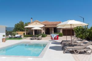 a swimming pool with lounge chairs and an umbrella at Idothea Stone Villa in Kalpaki