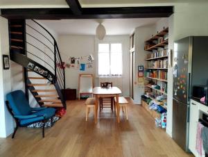 uma sala de estar com uma mesa e uma escada em espiral em Maison avec jardin au calme em Nantes