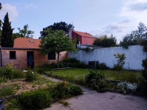 um quintal com uma casa de tijolos e uma cerca em Maison avec jardin au calme em Nantes