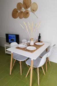 una mesa blanca con sillas y una botella de vino en Charmant Appartement Casa Freesia Caleta avec piscine, en Caleta de Fuste