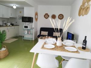 a white table with white plates and chairs in a kitchen at Charmant Appartement Casa Freesia Caleta avec piscine in Caleta De Fuste