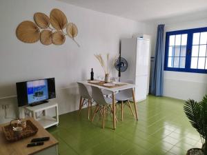a living room with a table and chairs and a television at Charmant Appartement Casa Freesia Caleta avec piscine in Caleta De Fuste