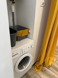 a washing machine in a room with a yellow curtain at Appartement • Six Fours Les plages in Six-Fours-les-Plages