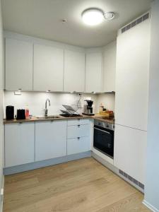 a kitchen with white cabinets and a sink and a stove at New Magnificent view apartment Near the centre in Tromsø