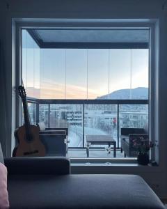 una sala de estar con una guitarra frente a una gran ventana en New Magnificent view apartment Near the centre, en Tromsø