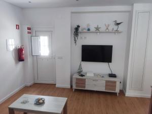 a living room with a flat screen tv on a white wall at Cabana Sete Ondas in Nazaré