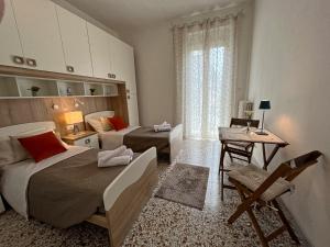 a bedroom with two beds and a desk and a window at Appartamento Nautes in San Benedetto del Tronto