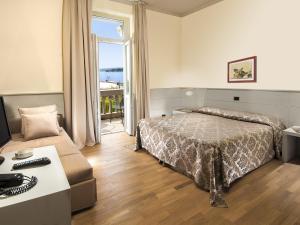 トスコラーノ・マデルノにあるHotel Milanoのベッドとソファ付きのホテルルーム