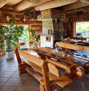ein Esszimmer mit einem großen Holztisch mit Bänken in der Unterkunft Wilcza Jama - domki z bali in Lutowiska