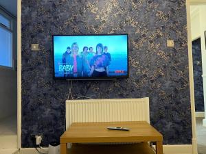 a flat screen tv on a wall with a table at Lovely Entire Flat in Kings Cross in London