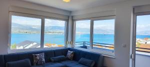 ein Wohnzimmer mit einem blauen Sofa und großen Fenstern in der Unterkunft Apartmani Ive in Trogir