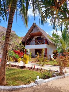 a house with palm trees in front of it at Queen of Sheba Beach Lodge in Pongwe