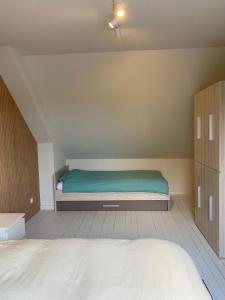 1 dormitorio con 1 cama con manta verde en De Scheure, charmant vakantiehuisje midden in de natuur en Alveringem