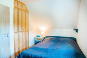 1 dormitorio con cama azul y puerta de madera en Tátorján Vendégház, en Balatonkenese