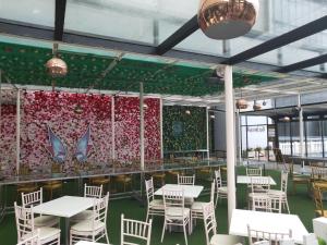 a dining room with white tables and chairs and a wall of flowers at Genting HillTop @ Ion Highland Resort in Genting Highlands