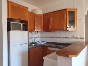 una cucina con armadi in legno e frigorifero bianco di Luz de sal. Alojamiento, recreo, naturaleza y más! a Lo Pagán