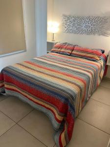 een bed met een kleurrijke deken erop in een kamer bij Monoambiente C/ Cochera - La Perla, A 250m De La Playa in Mar del Plata