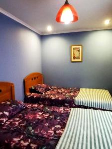 a bedroom with two beds and a blue wall at Cabaña en Recinto con piscina y tinaja in Chillán