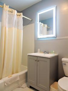 uma casa de banho com um lavatório, um WC e um espelho. em Windsor Motel em Groton